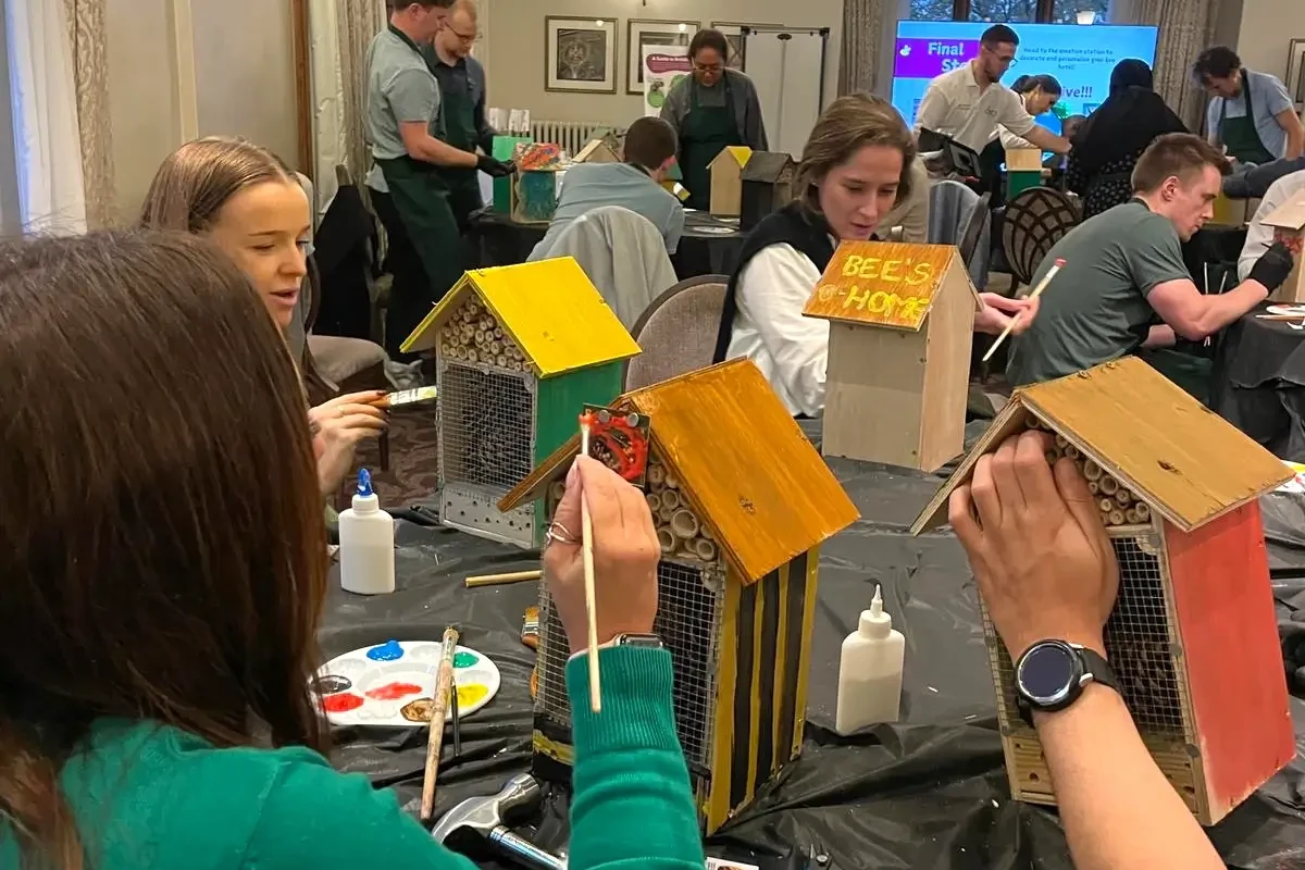 Team building participants painting bee hotels