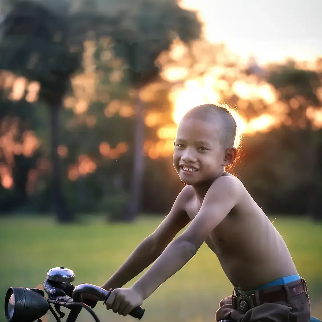 Child smiling on bike at sunset after he received a bike from the Charity Bike Build team building event