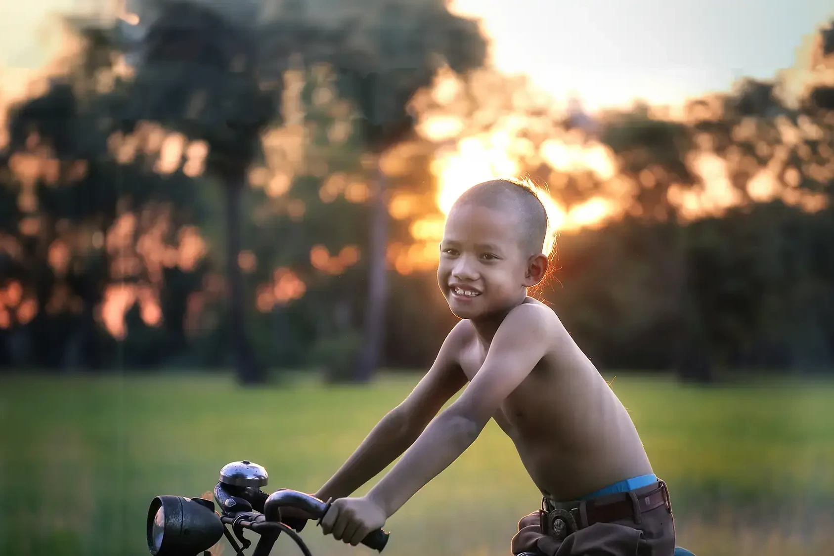 Child smiling on bike at sunset after he received a bike from the Charity Bike Build team building event