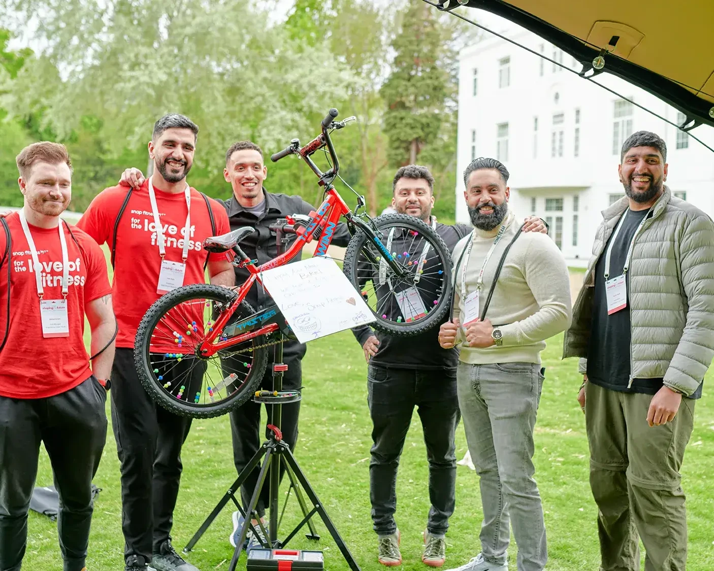 Team building participants holding charity bike in outdoor event