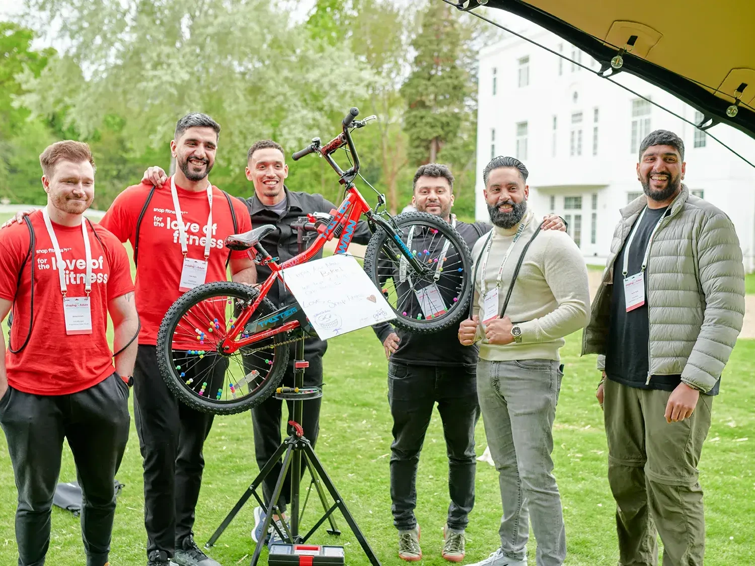 Team building participants holding charity bike in outdoor event