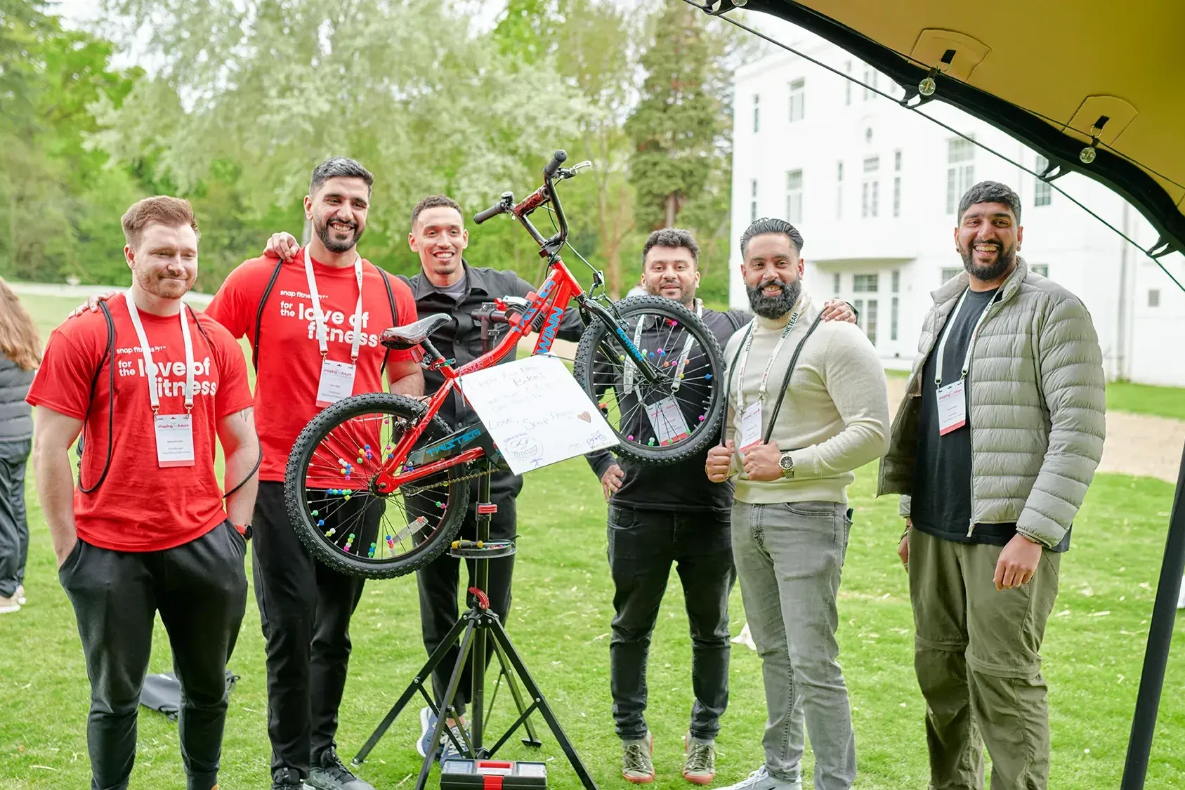 Team building participants holding charity bike in outdoor event