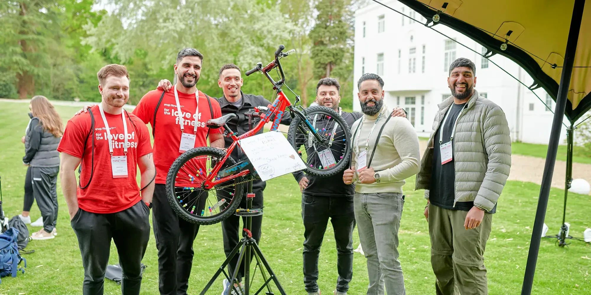 Team building participants holding charity bike in outdoor event