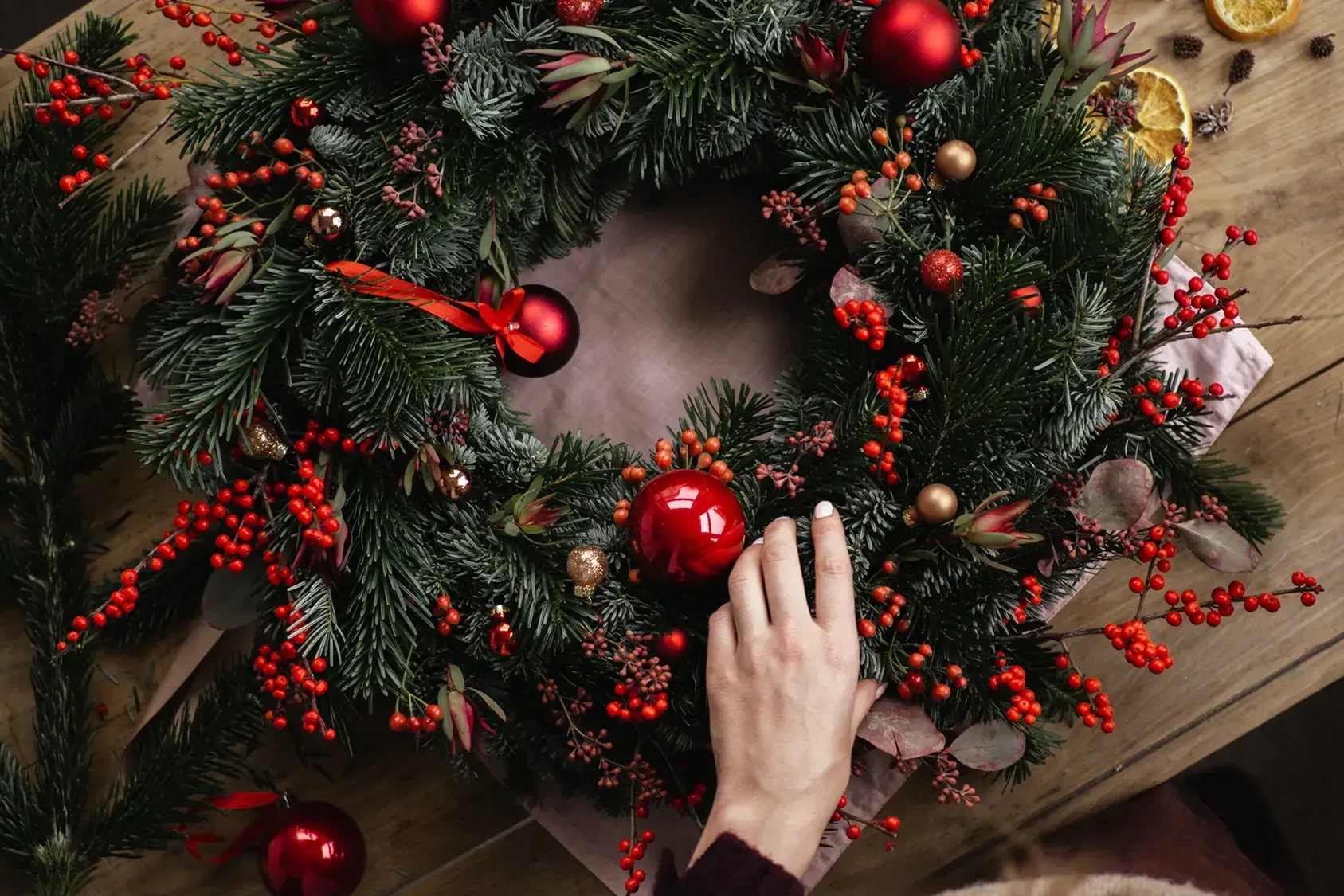 Red baubles on green pine wreath in wreath making class