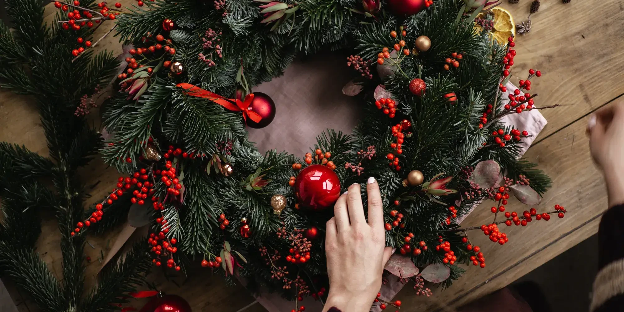 Red baubles on green pine wreath in wreath making class