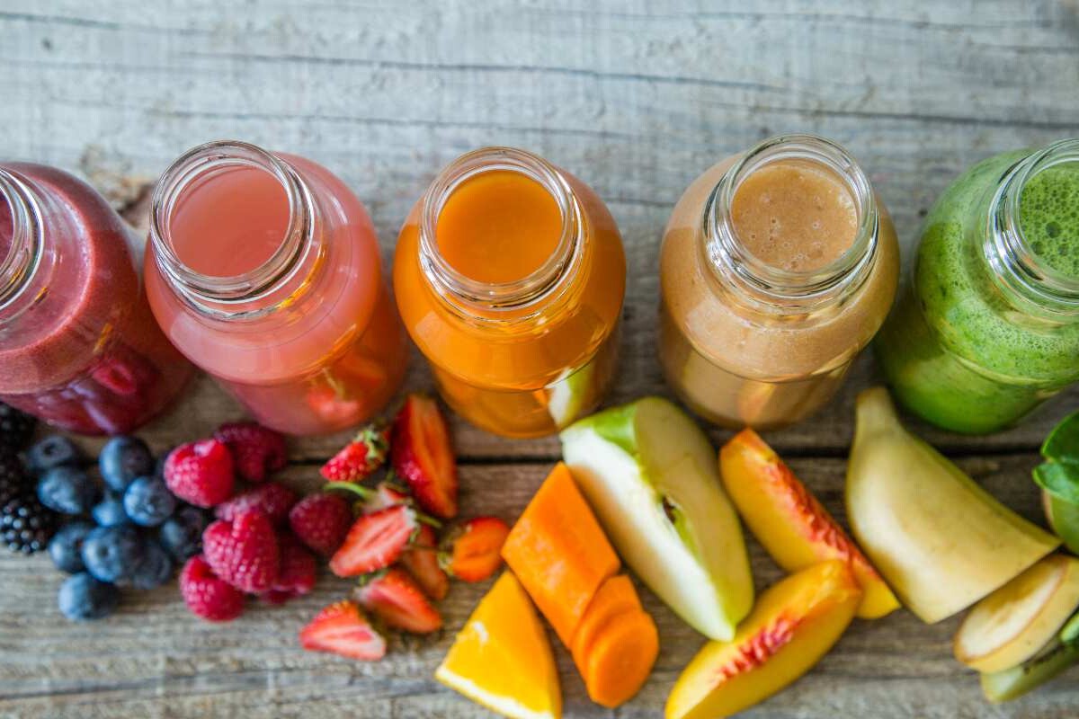 Overhead shot of different colour and flavoured smoothies with chopped ingredients