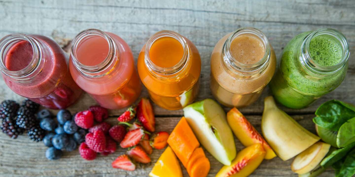 Overhead shot of different colour and flavoured smoothies with chopped ingredients