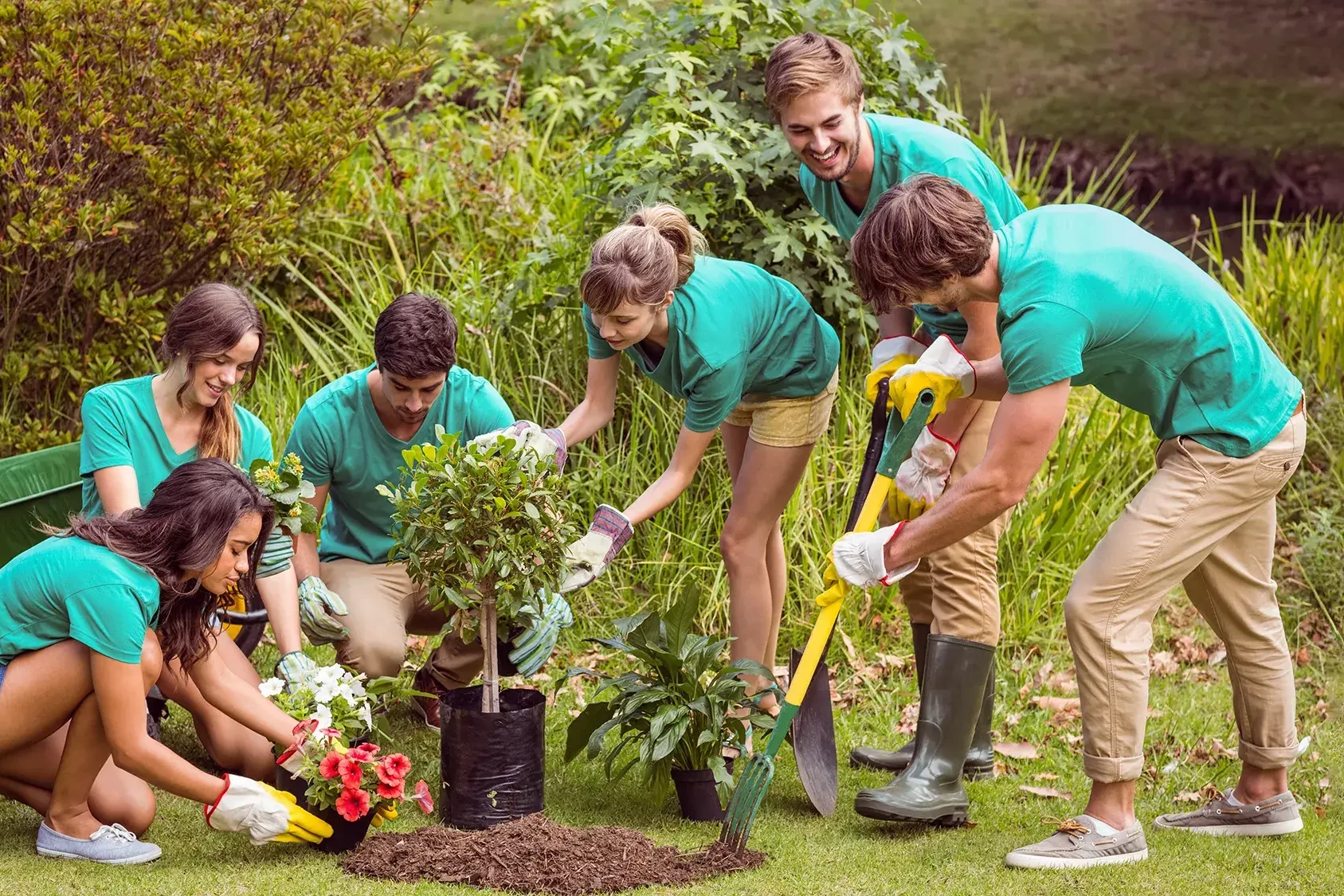 Group of people planting flowers in community cleaning up team building event