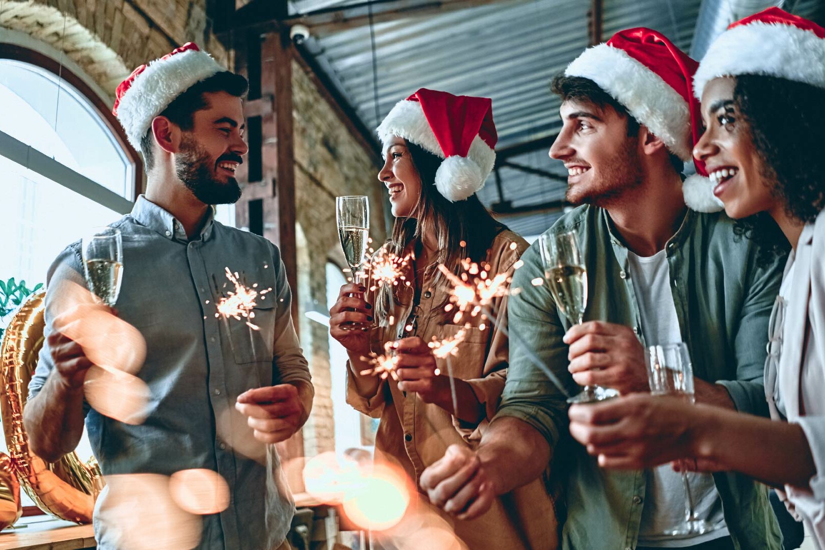 Group of people celebrating Christmas with a glass of Prosecco and a sparkler.