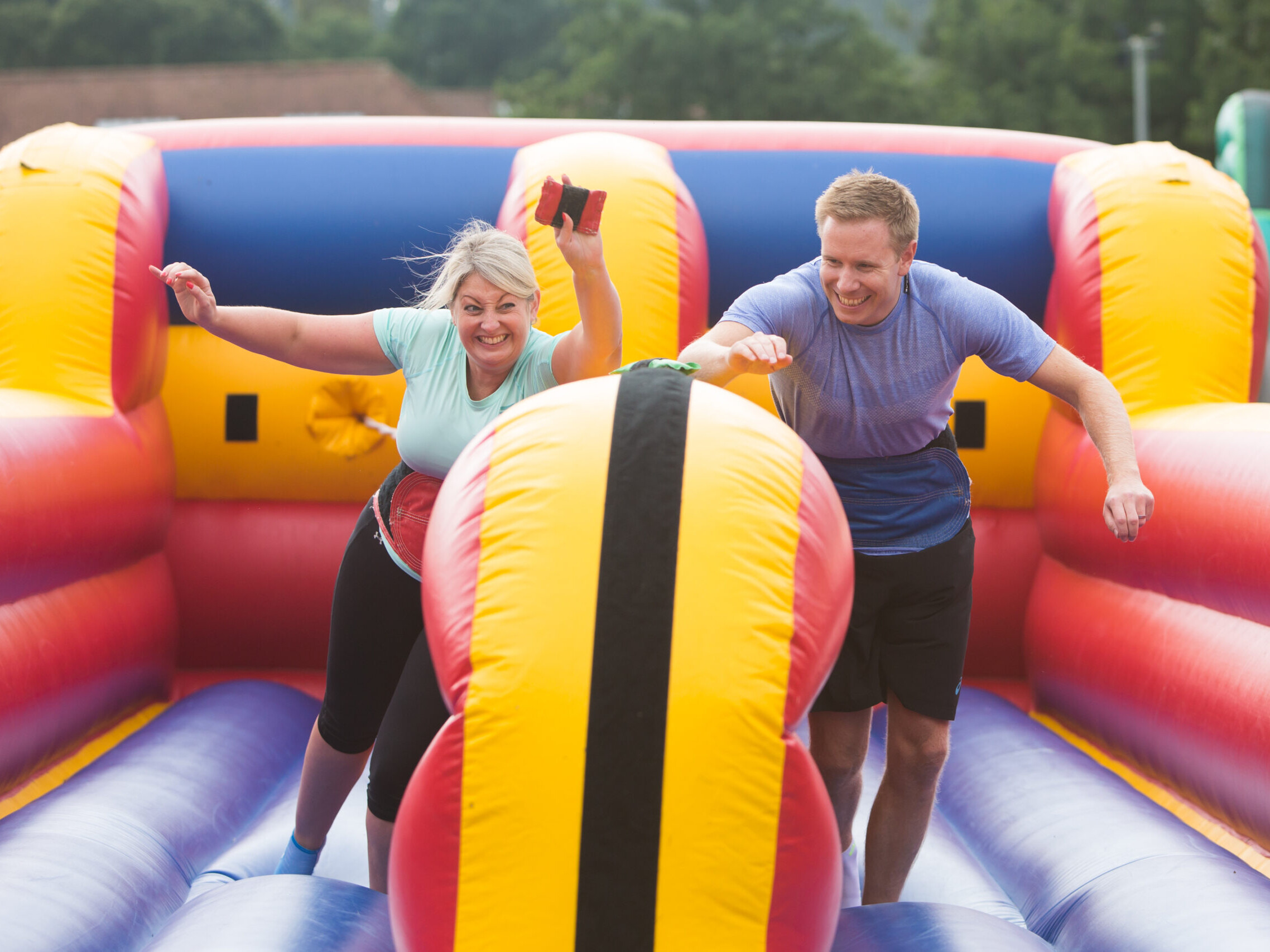 People having fun while competing in team building competition on inflatable course