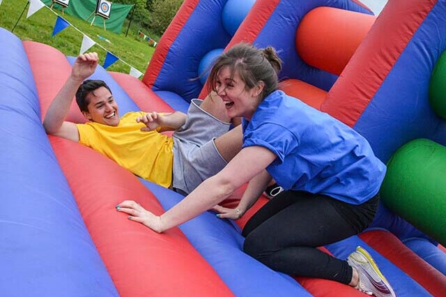 Two colleagues laughing on a giantn inflatable assault course