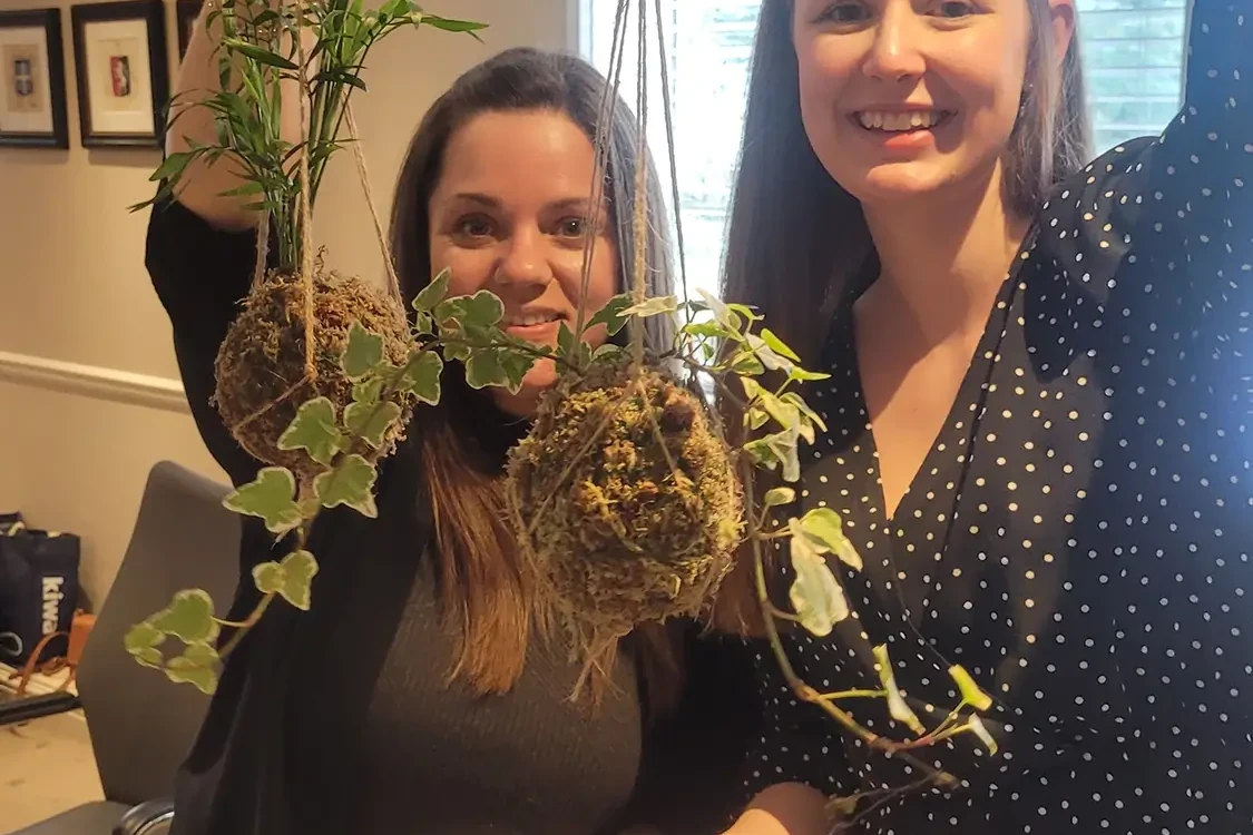 two women showing their kokedama balls after sustainability team building event