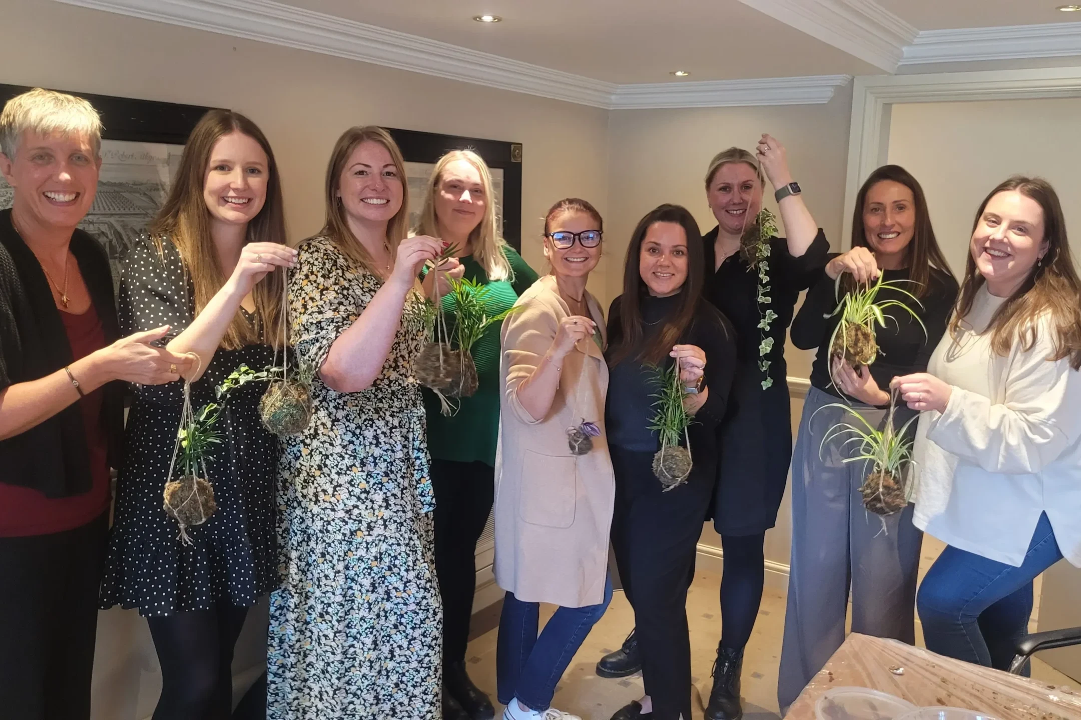 Team of women showcasing their Kokedama plants after sustainability team building event