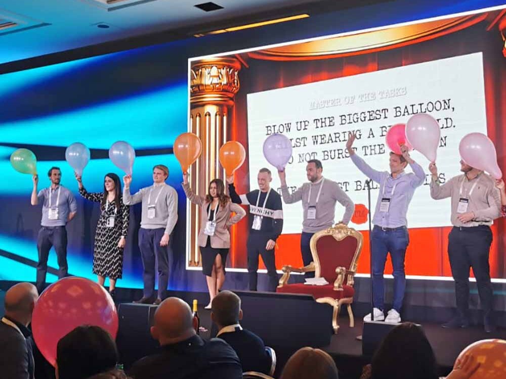 Colleagues stood on a stage with balloons in their hands