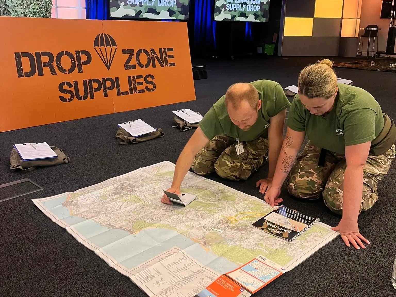 Operation supply drop participants in army outfits reading a map on the floor