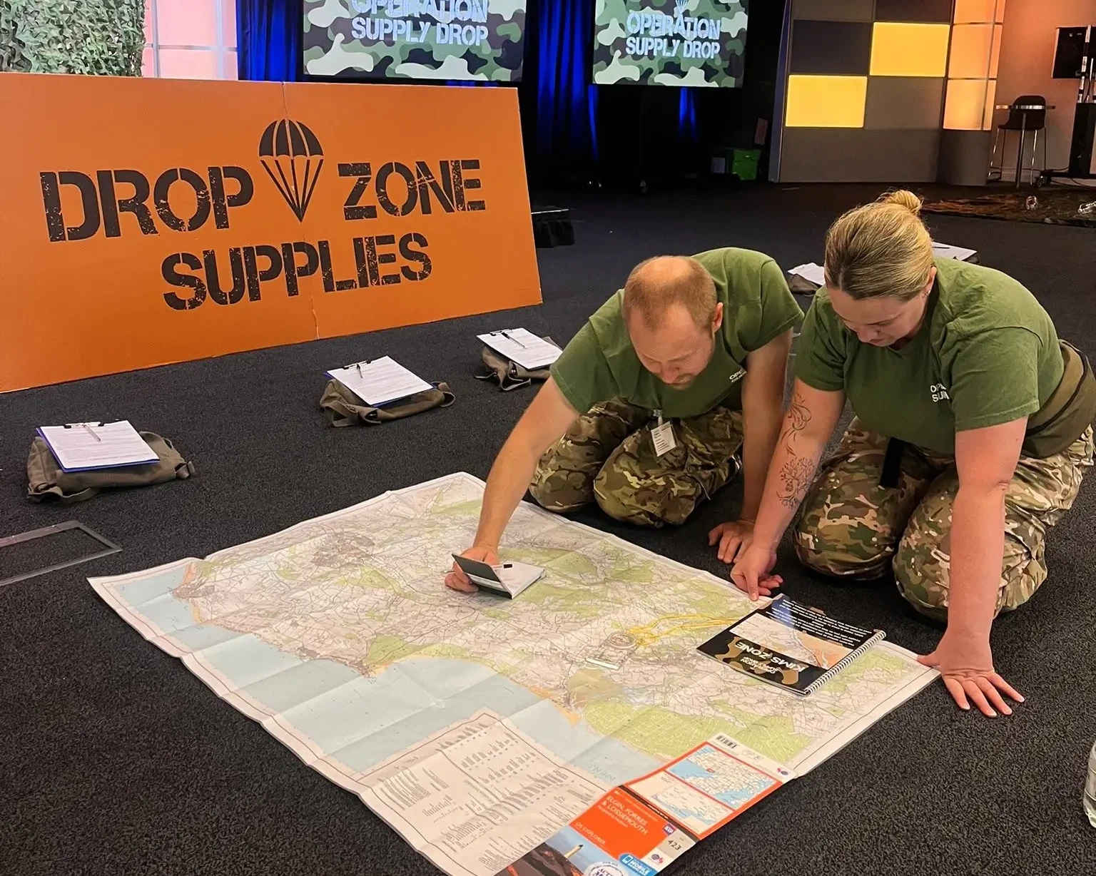 Operation supply drop participants in army outfits reading a map on the floor