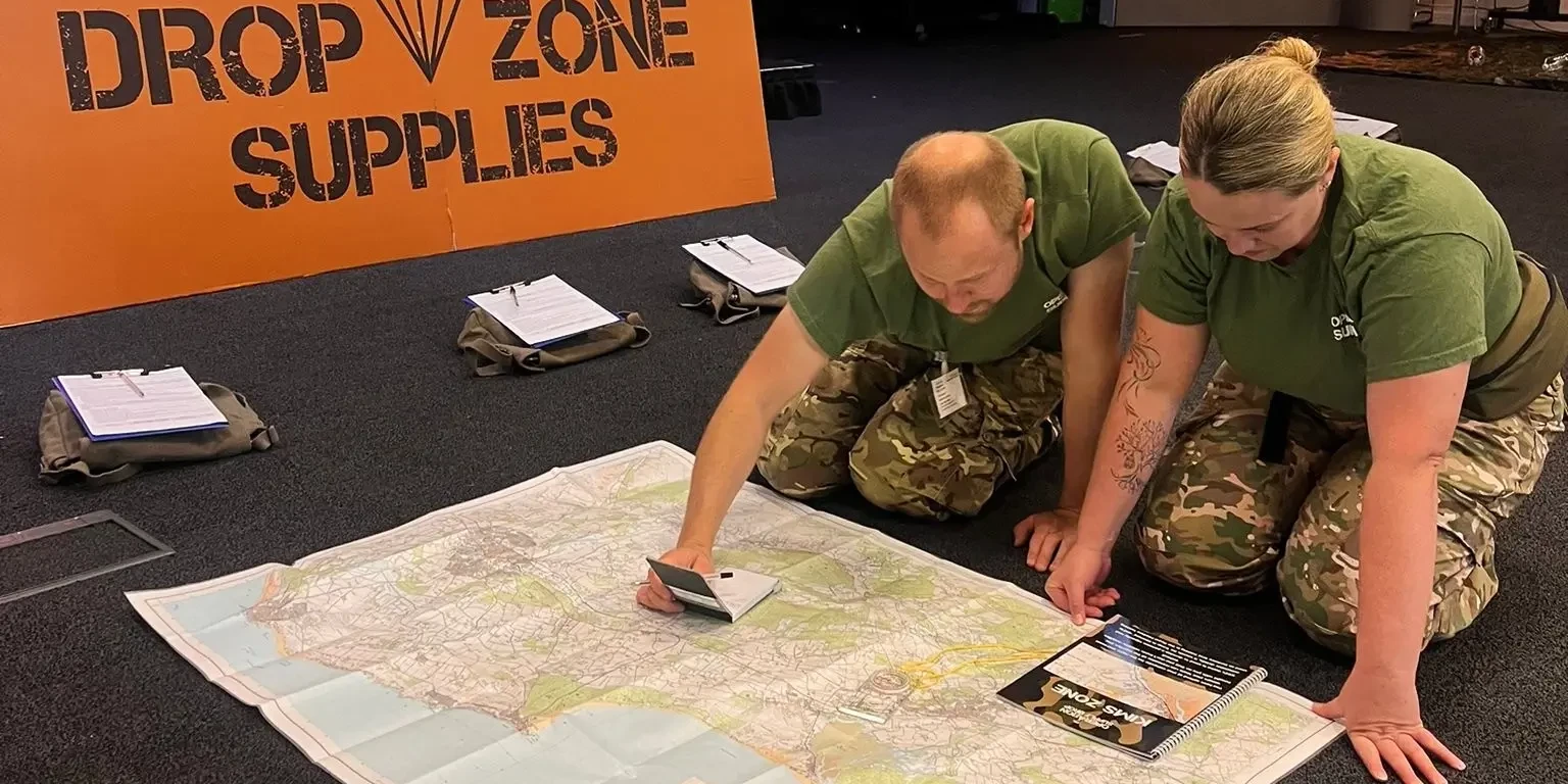 Operation supply drop participants in army outfits reading a map on the floor