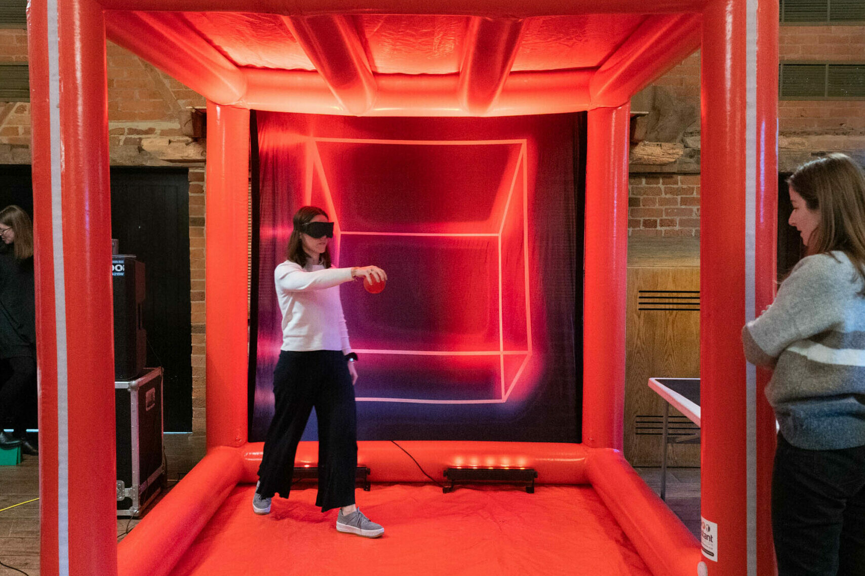 A women playing the ball drop game inside a giant red inflatable cube.