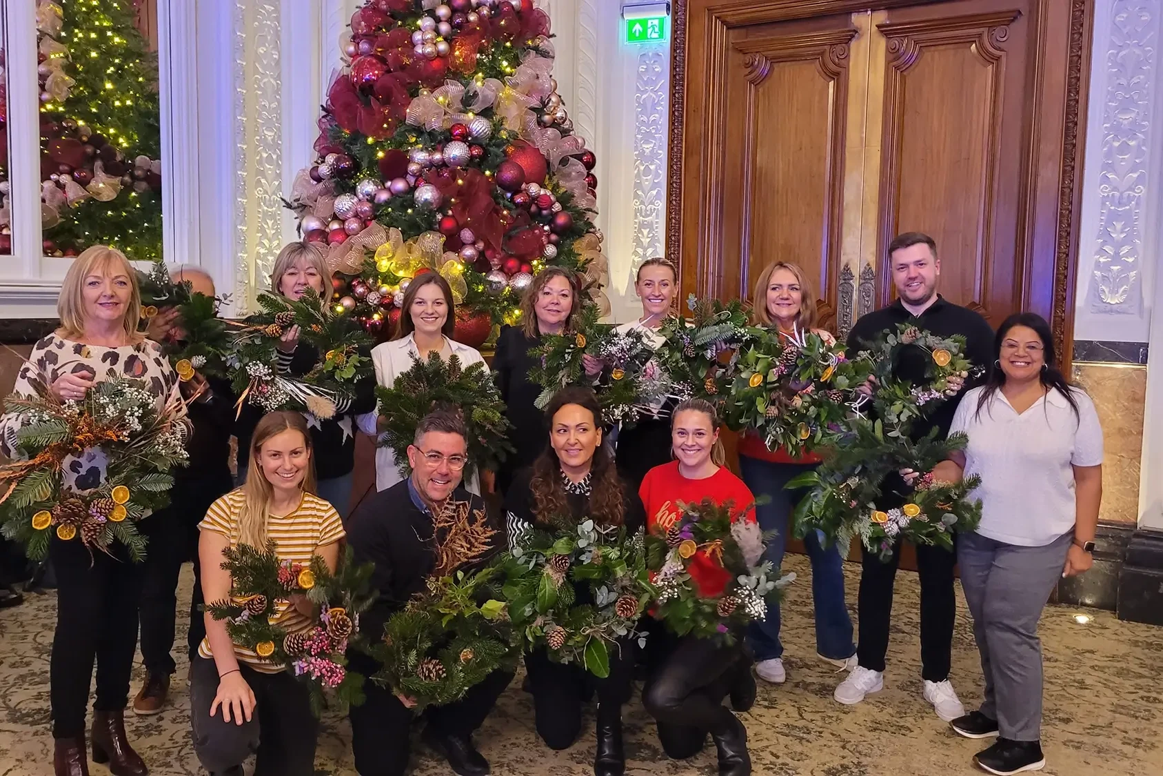 Team holding wreaths in front of Christmas tree