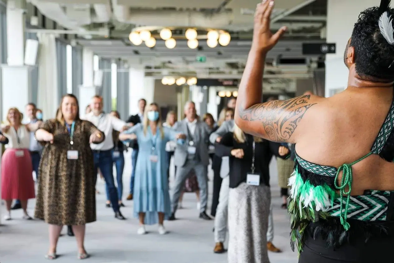 Haka performer guiding conference audience into haka dance