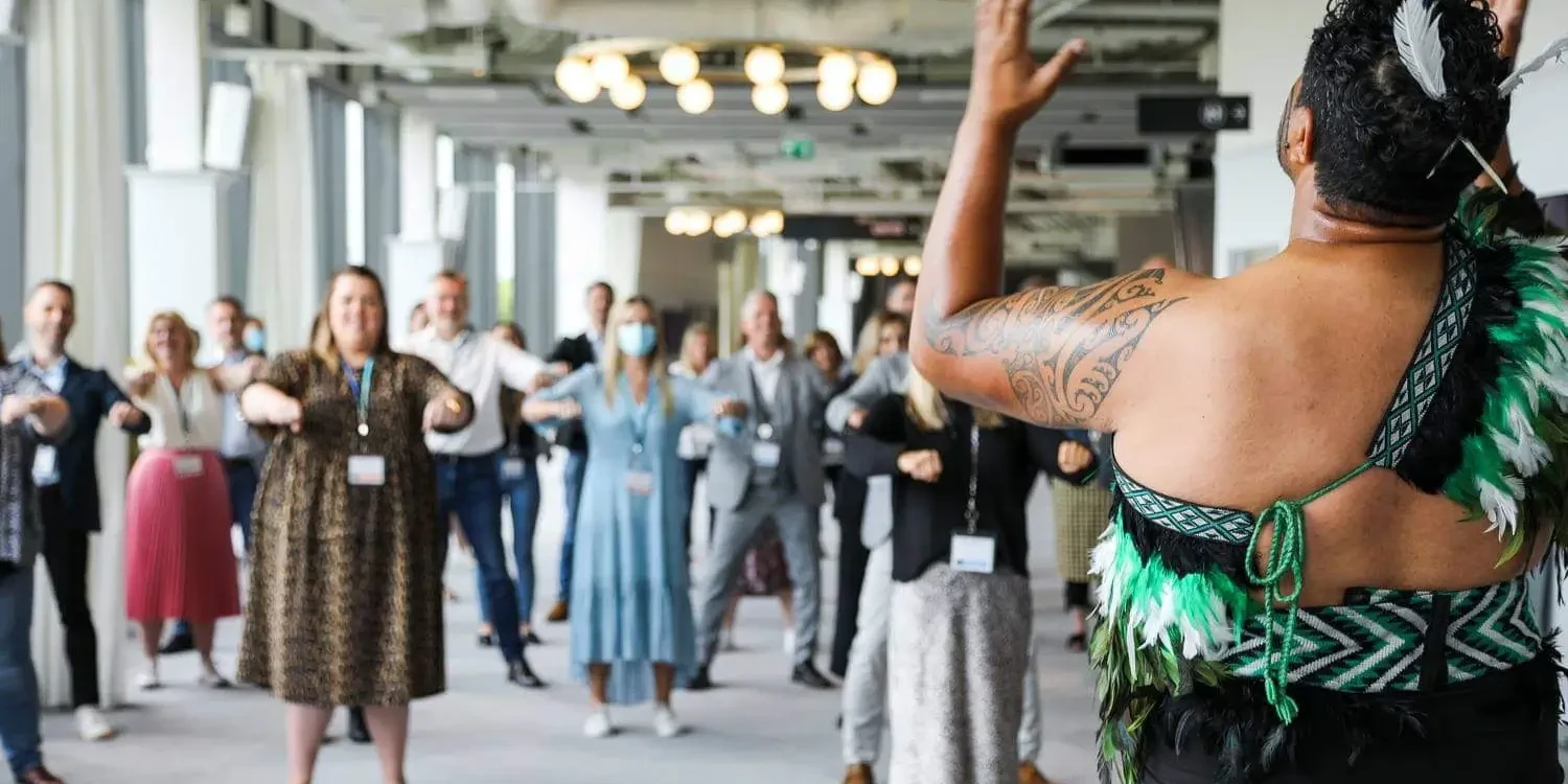 Haka performer guiding conference audience into haka dance