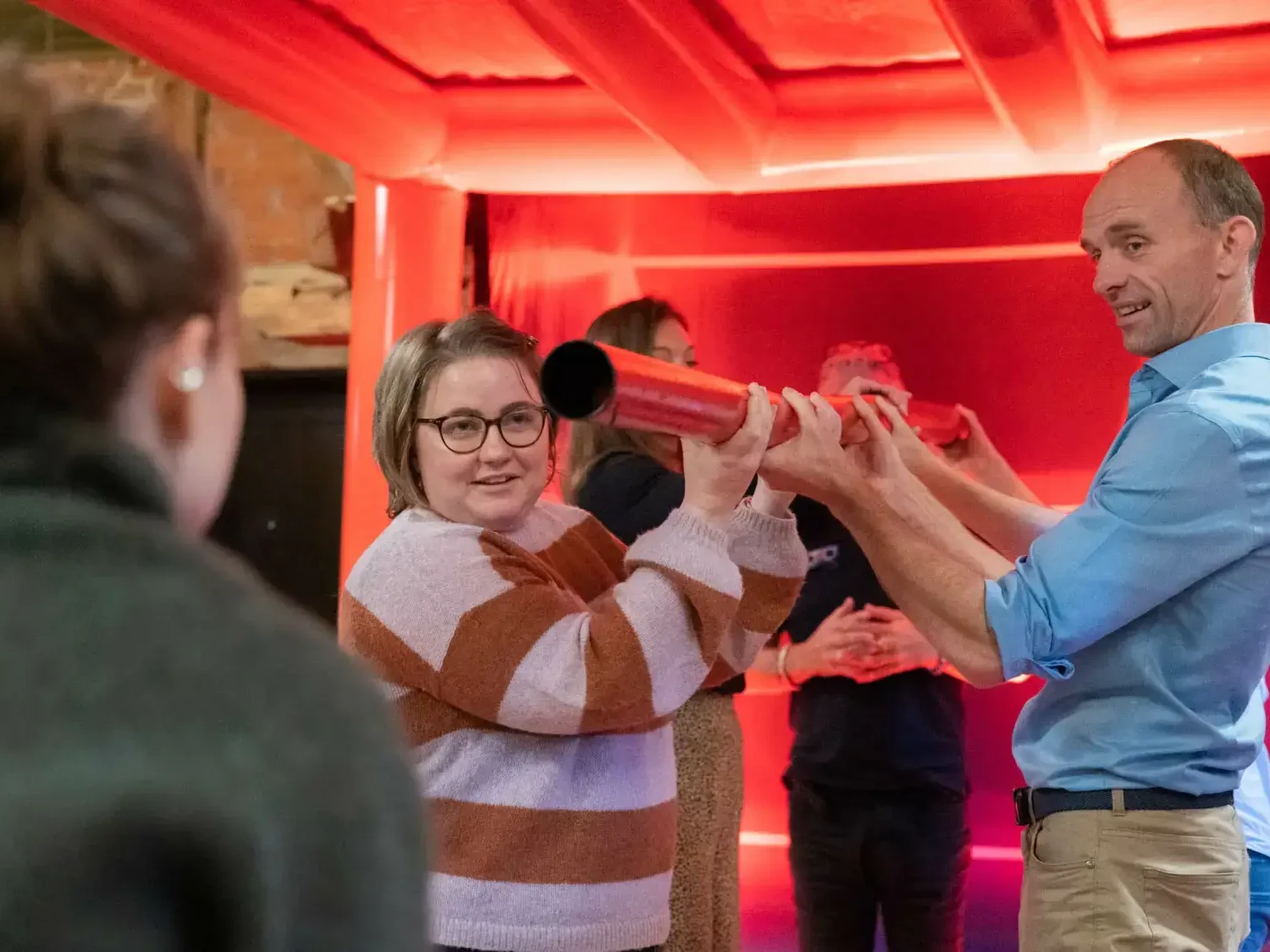 Happy people in team building game under giant red cube