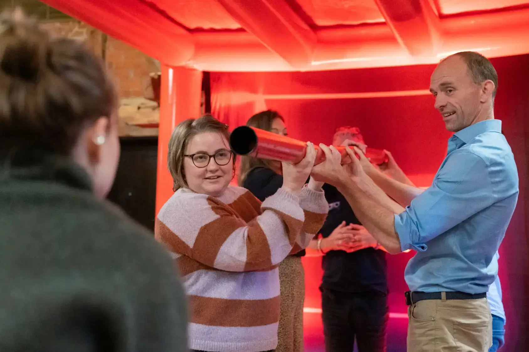 Happy people in team building game under giant red cube