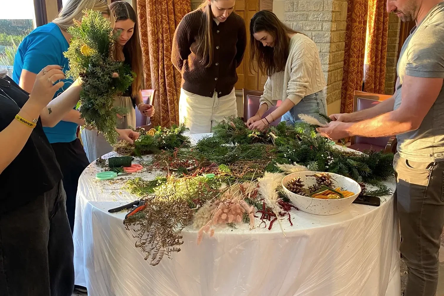 Wreath Making participants around the crafts table collaborating