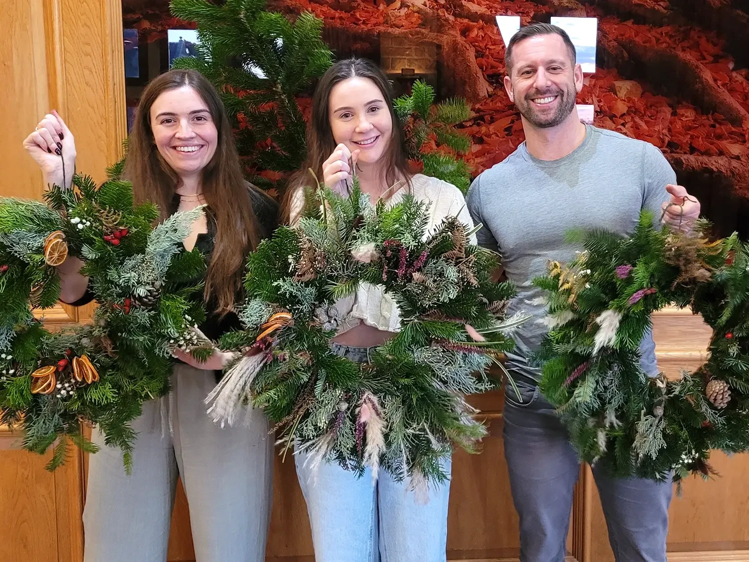 Wreath Making participants smiling and holding up their wreaths