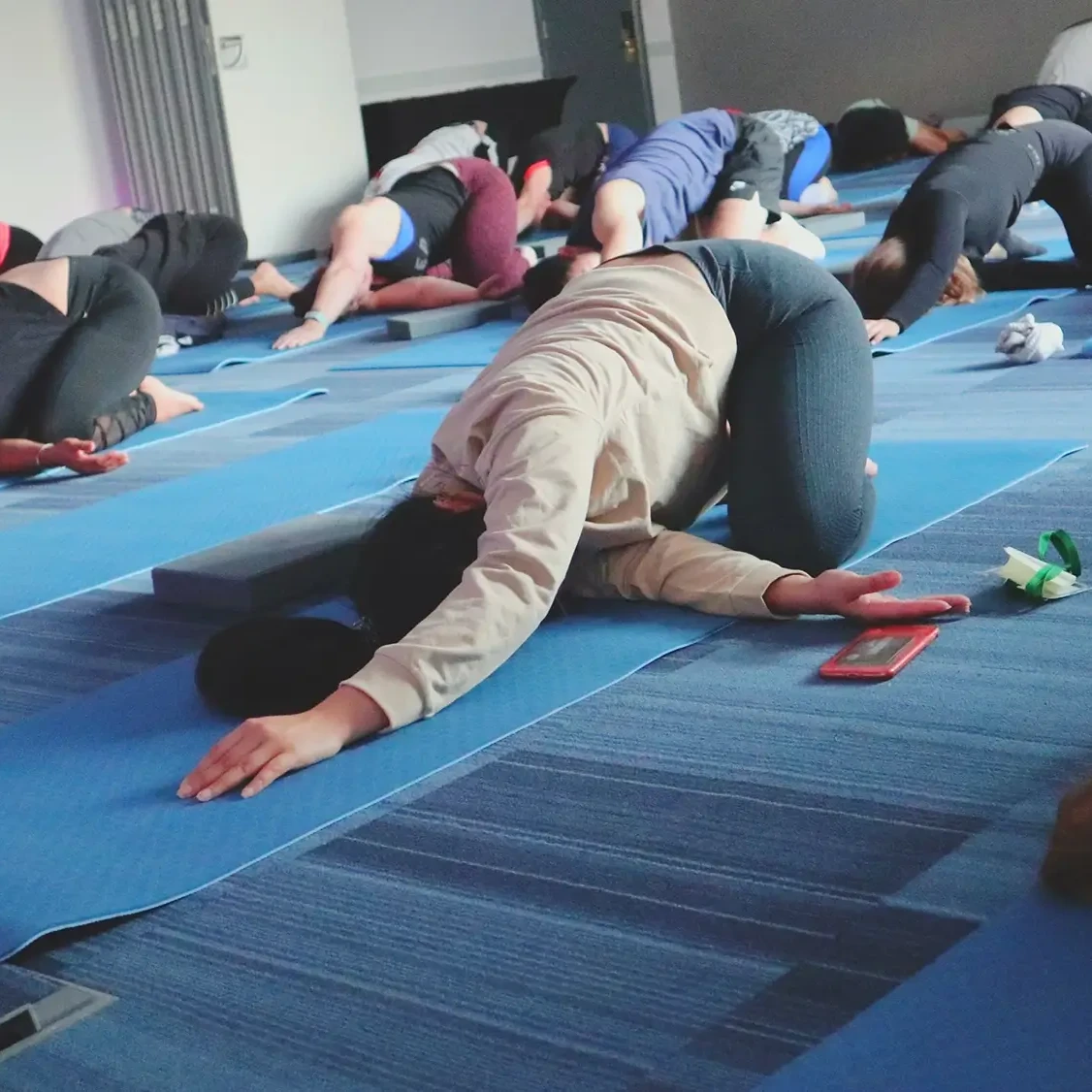 Corporate team participating in Yoga team building class doing stretches on the floor