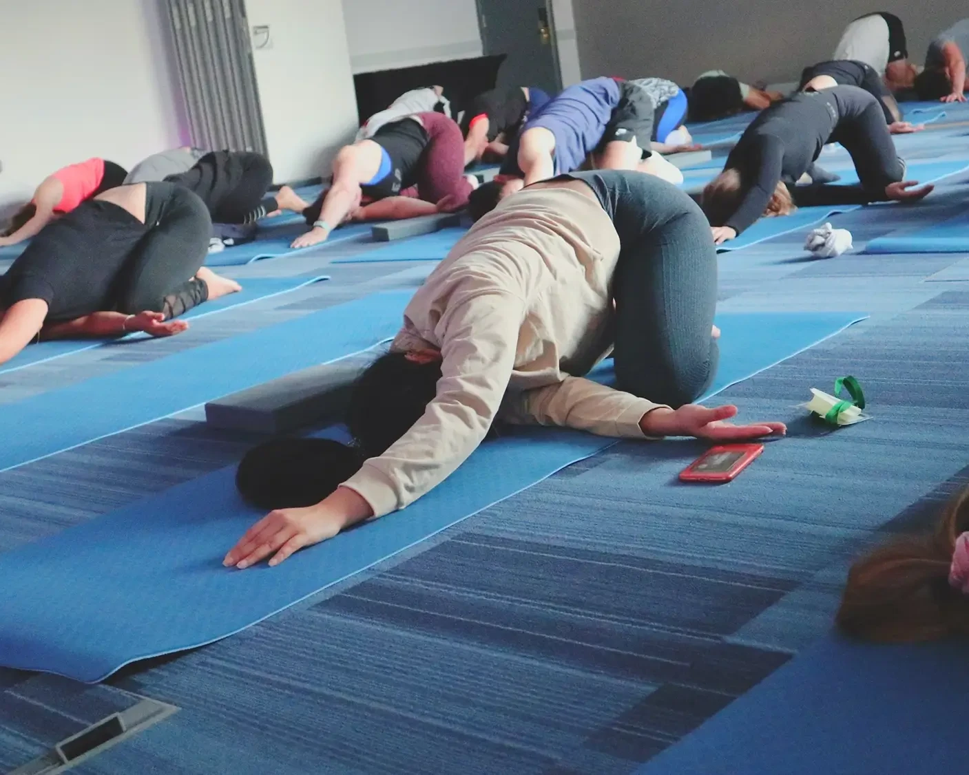 Corporate team participating in Yoga team building class doing stretches on the floor