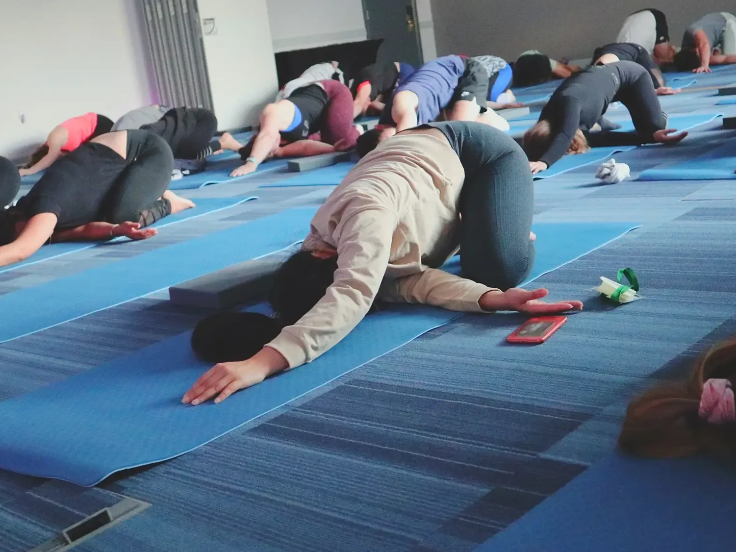 Corporate team participating in Yoga team building class doing stretches on the floor