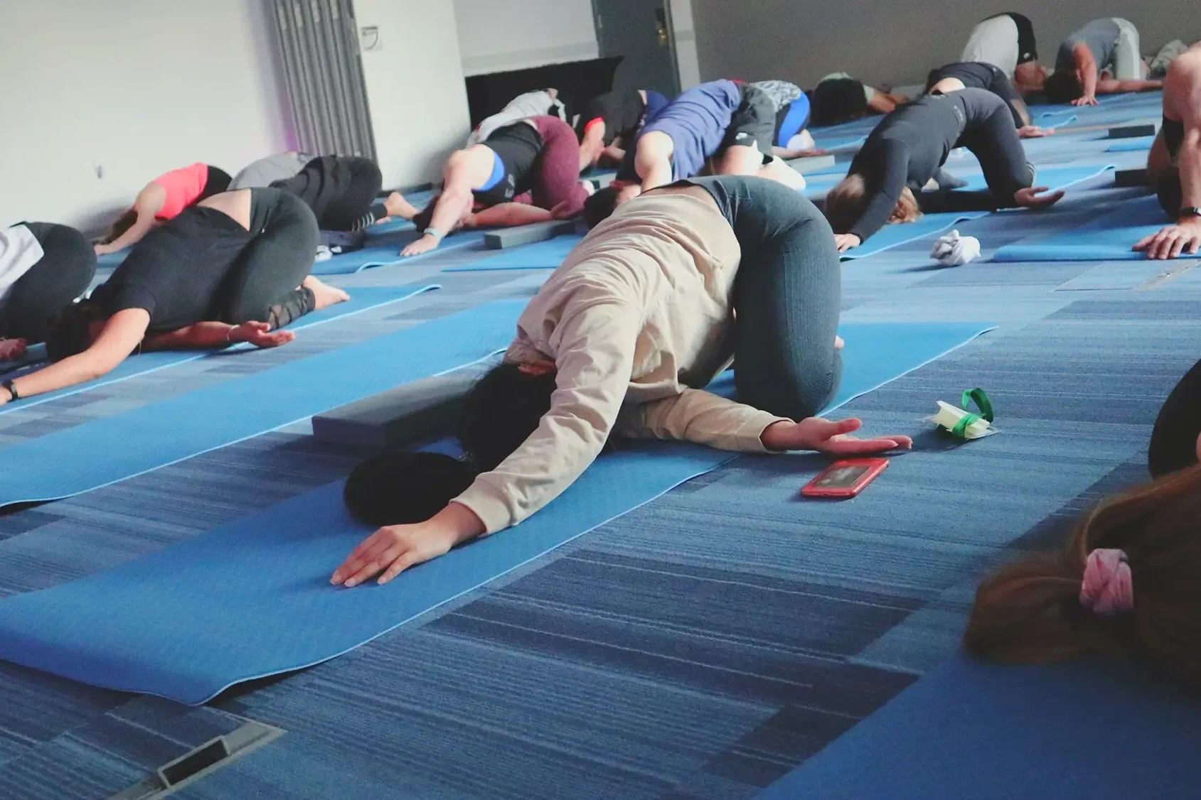 Corporate team participating in Yoga team building class doing stretches on the floor