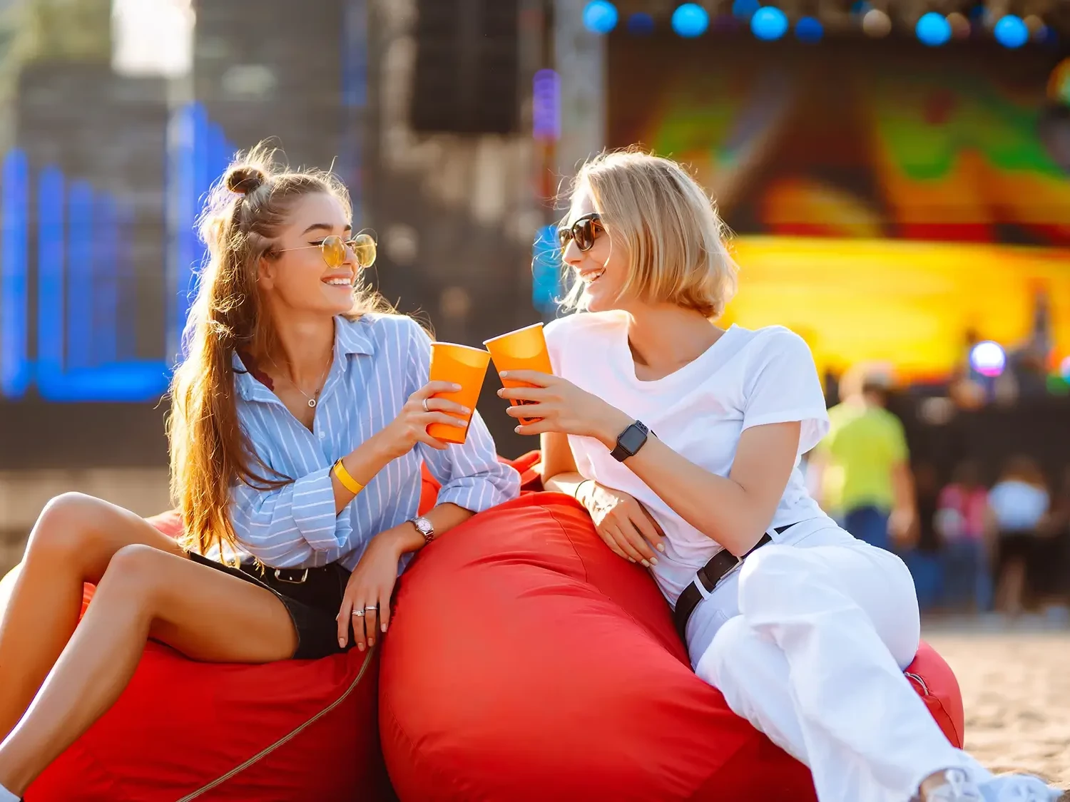 women sitting on bean nags smiling with drink in hand during company fun day