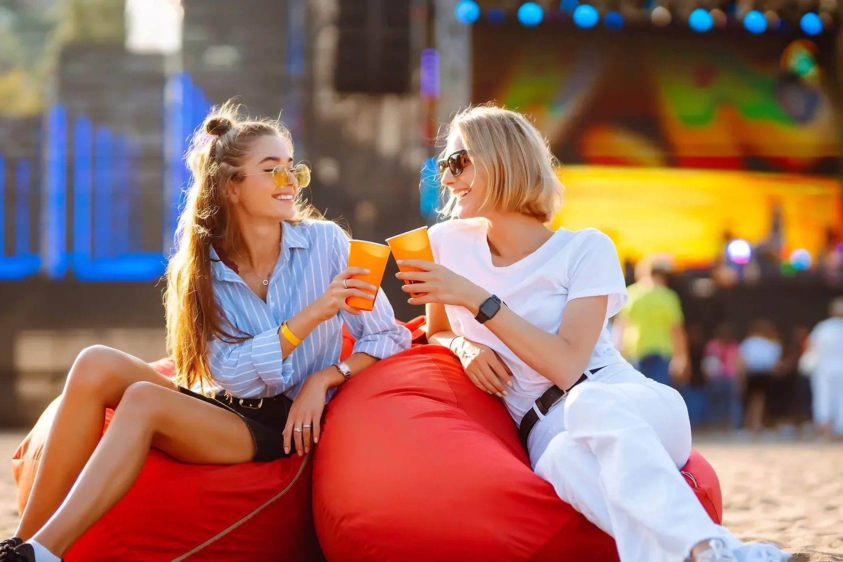 women sitting on bean nags smiling with drink in hand during company fun day