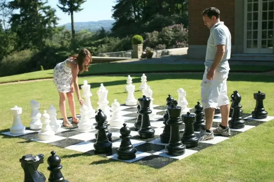 woman and man playing giant chess on green grass in outside corporate fun day