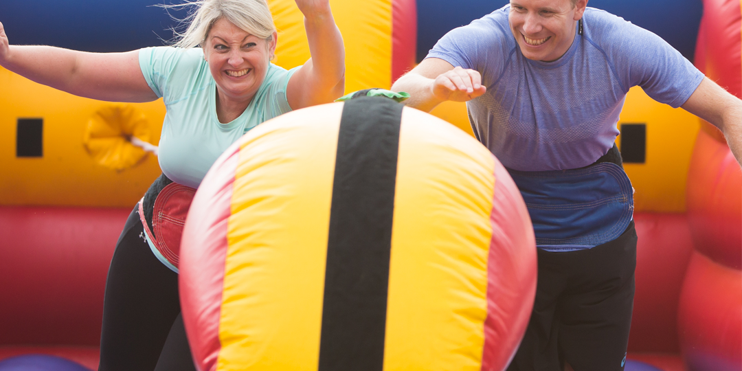 People having fun while competing in team building competition on inflatable course