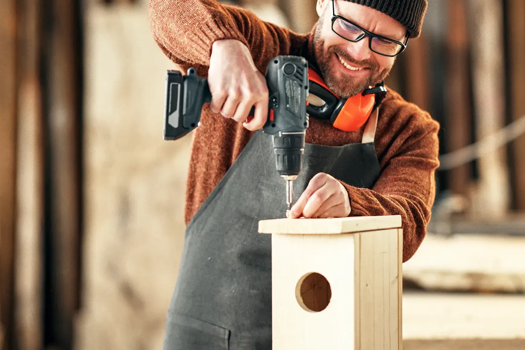 man drilling birdhouse in sustainability workshop
