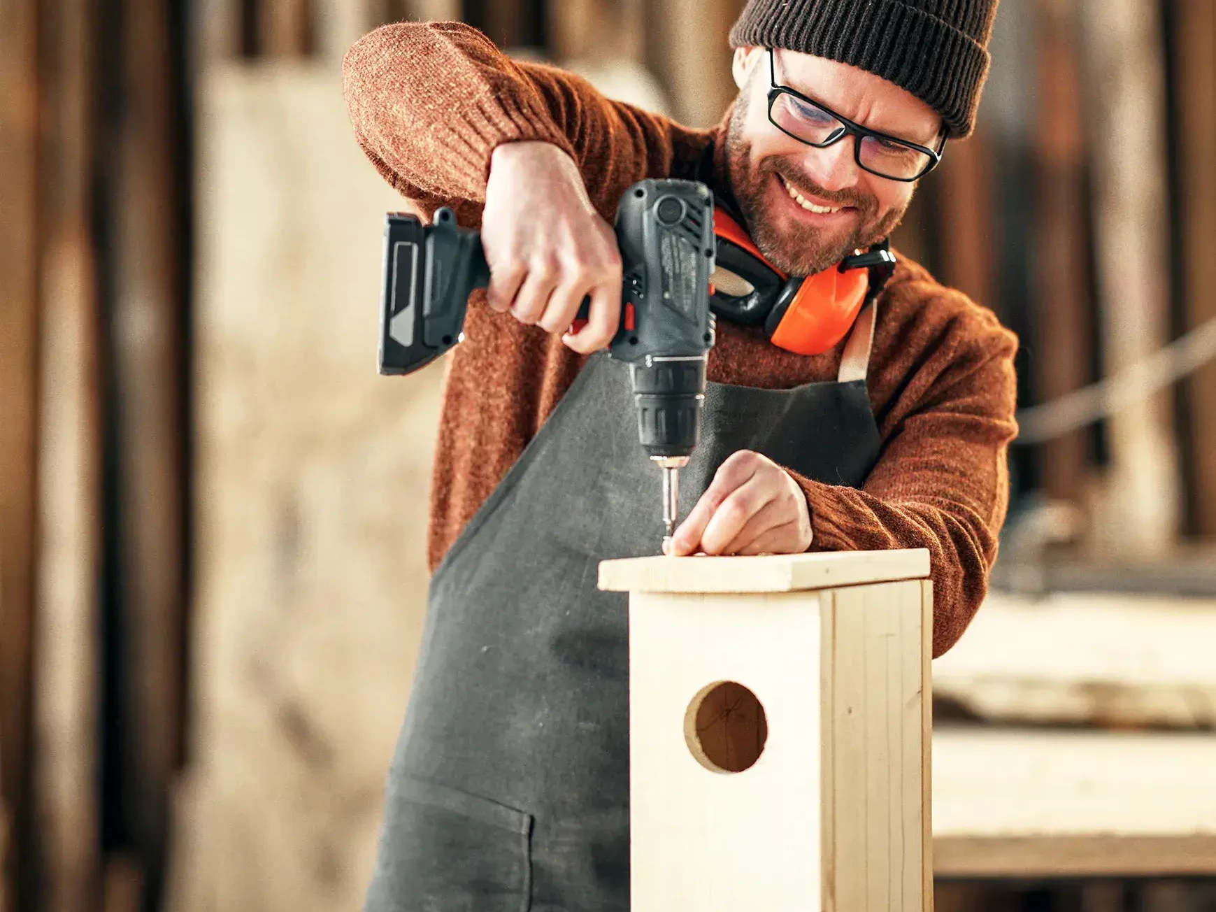 man drilling birdhouse in sustainability workshop