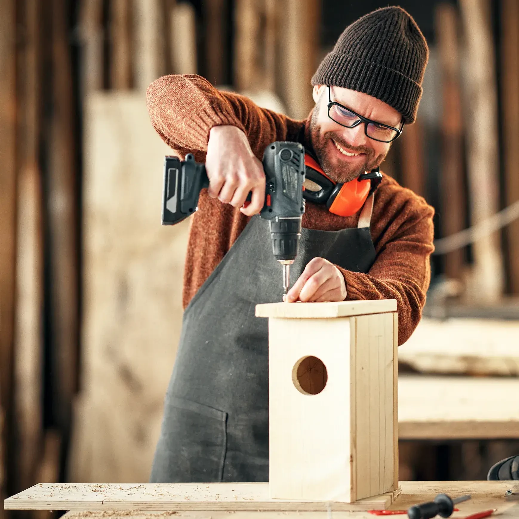 man drilling birdhouse in sustainability workshop