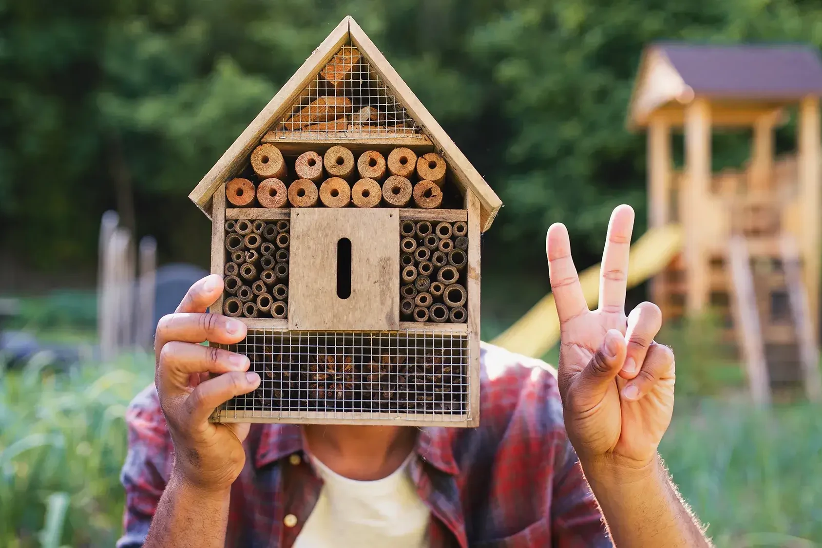 man holding bee hotel to his face in sustainability wworkshop